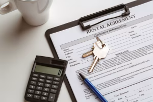 A car rental agreement form on a clipboard with keys, a pen, and a calculator placed on a white table next to a coffee cup.